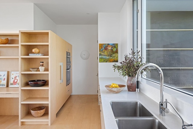 kitchen featuring open shelves, modern cabinets, a sink, light wood-type flooring, and double oven