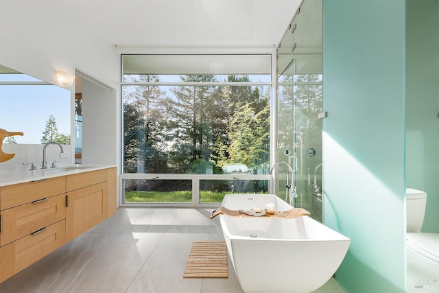 full bath featuring toilet, a soaking tub, vanity, and tile patterned flooring