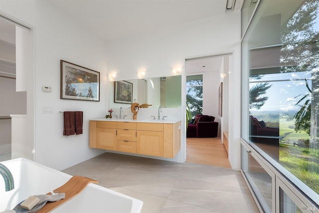 bathroom with a sink, double vanity, and a soaking tub