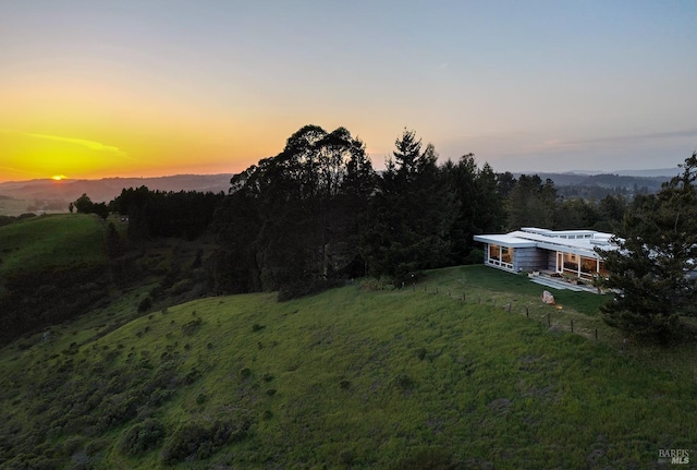 yard at dusk featuring a wooded view
