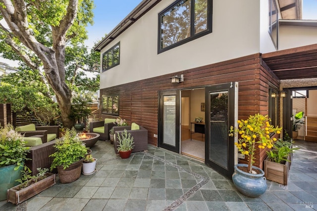 exterior space featuring an outdoor living space with a fire pit, a patio, and stucco siding