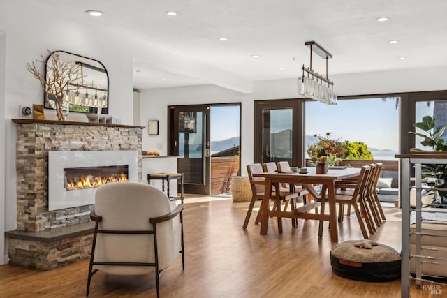 dining area with a healthy amount of sunlight, recessed lighting, a stone fireplace, and wood finished floors