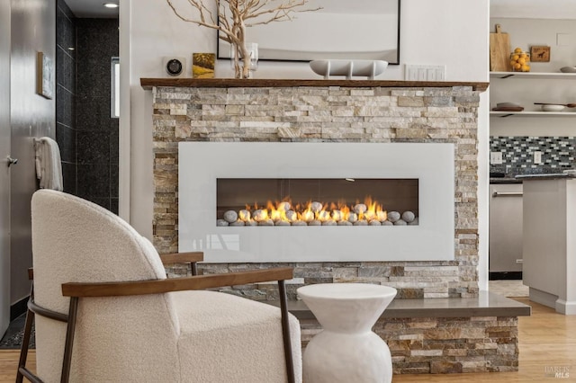 interior space with a stone fireplace, wood finished floors, and tasteful backsplash
