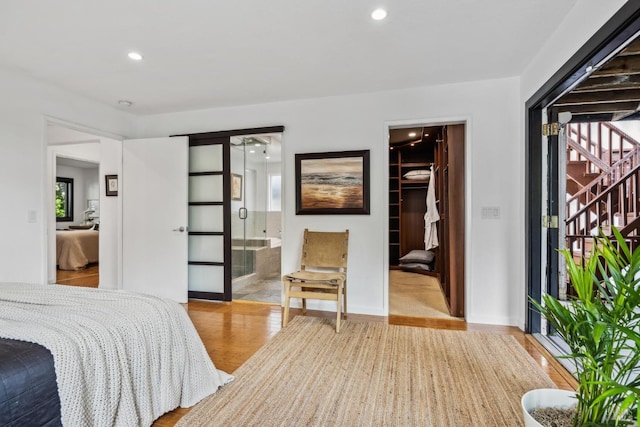 bedroom featuring a closet, wood finished floors, a walk in closet, recessed lighting, and ensuite bath