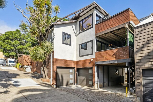 view of front of home featuring an attached garage, driveway, and a balcony