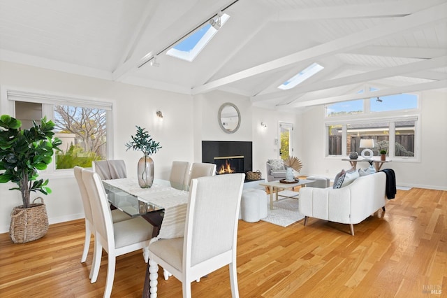 13 Leeward Rd, Belvedere, CA 94920 - dining area featuring vaulted ceiling with skylight, rail lighting, light wood-style floors, and a lit fireplace