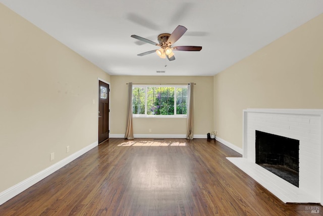 unfurnished living room with a brick fireplace, baseboards, wood finished floors, and ceiling fan