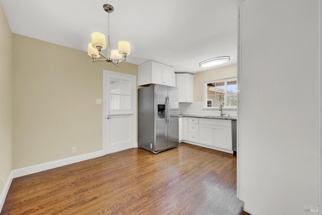 kitchen with dark wood finished floors, tasteful backsplash, a chandelier, a sink, and stainless steel appliances