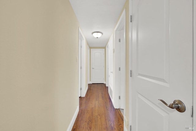 hallway featuring dark wood-type flooring and baseboards