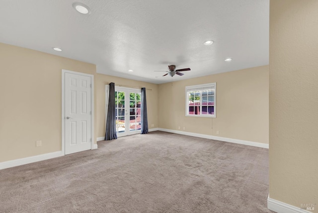 carpeted spare room with a wealth of natural light, a ceiling fan, and baseboards