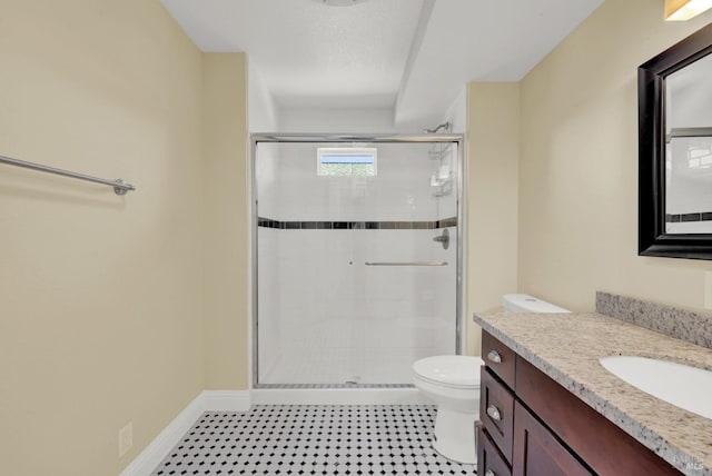full bath with a shower stall, vanity, baseboards, and toilet