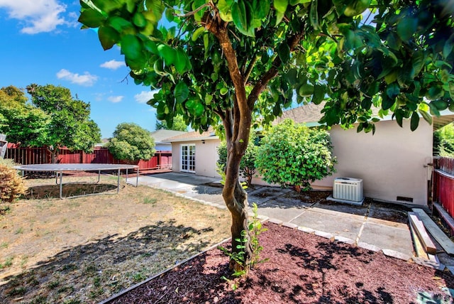 view of yard with central air condition unit, a trampoline, a patio area, and a fenced backyard