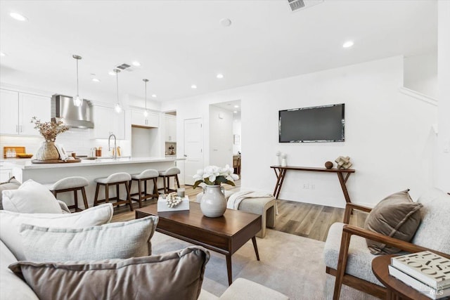 living room with visible vents, recessed lighting, and light wood-style floors