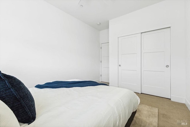 bedroom featuring light carpet, a closet, and baseboards