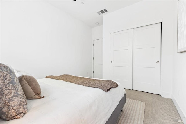 bedroom with a closet, light colored carpet, baseboards, and visible vents