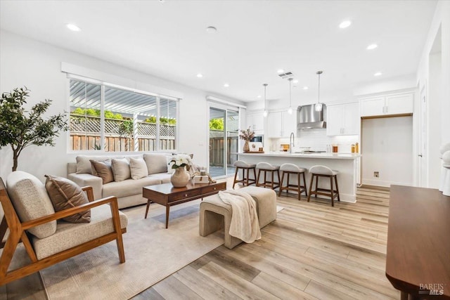 living room featuring light wood-style floors, visible vents, and recessed lighting