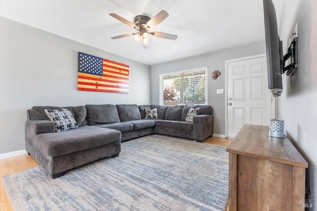 living room with baseboards, a ceiling fan, and light wood-style floors