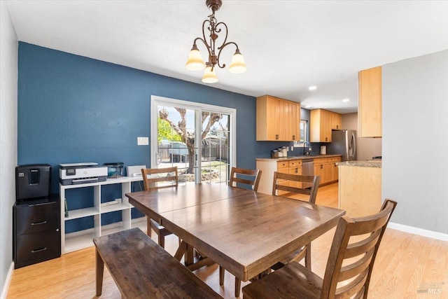 dining area featuring a chandelier, baseboards, and light wood-style flooring