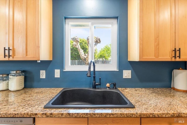 kitchen featuring dishwashing machine, a sink, and light brown cabinetry