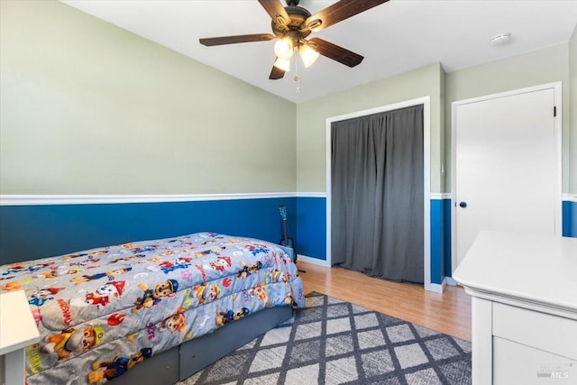 bedroom featuring ceiling fan, a closet, baseboards, and wood finished floors