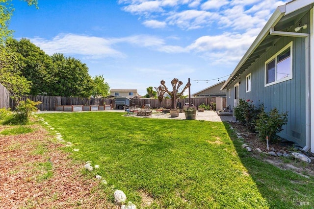 view of yard with a patio, a fenced backyard, and a fire pit