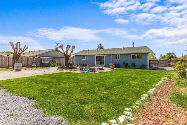back of house featuring a patio area, a fenced backyard, a fire pit, and a yard