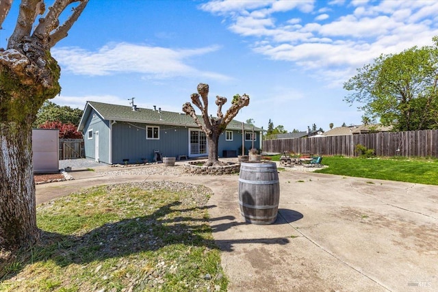 back of property featuring a patio area, a fire pit, a fenced backyard, and a yard