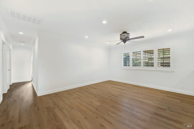 spare room featuring crown molding, visible vents, baseboards, and wood finished floors