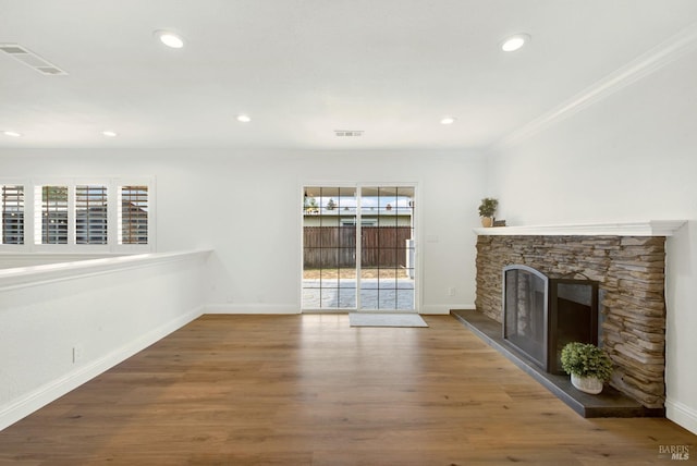 unfurnished living room with a wealth of natural light, visible vents, baseboards, and wood finished floors