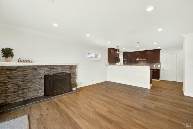 unfurnished living room with crown molding, wood finished floors, a fireplace, and baseboards