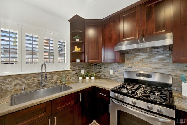 kitchen with tasteful backsplash, under cabinet range hood, stainless steel range with gas cooktop, and a sink