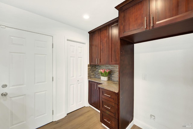 kitchen featuring baseboards, recessed lighting, light wood-style flooring, light stone countertops, and decorative backsplash