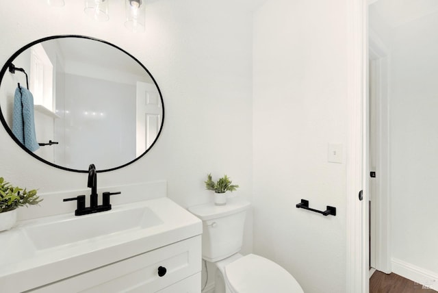 half bathroom with vanity, toilet, and wood finished floors