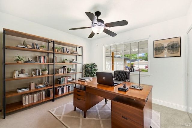 office featuring baseboards, a ceiling fan, and light carpet