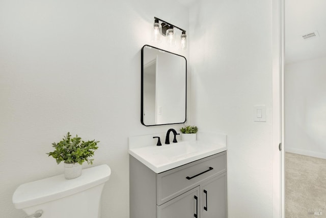 bathroom featuring toilet, vanity, and visible vents