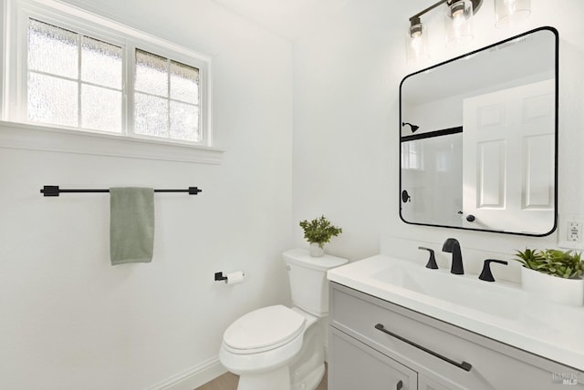 bathroom featuring vanity, baseboards, walk in shower, and toilet