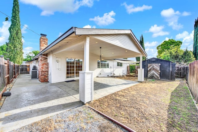 exterior space featuring a patio area, a fenced backyard, a storage shed, and a chimney