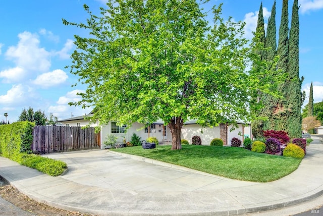 obstructed view of property with a front lawn, fence, and stucco siding