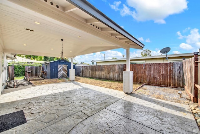 view of patio featuring a storage unit, a fenced backyard, and an outdoor structure