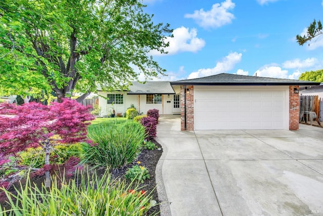 ranch-style house with concrete driveway, brick siding, fence, and an attached garage