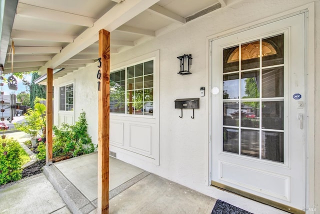 property entrance with a porch and stucco siding