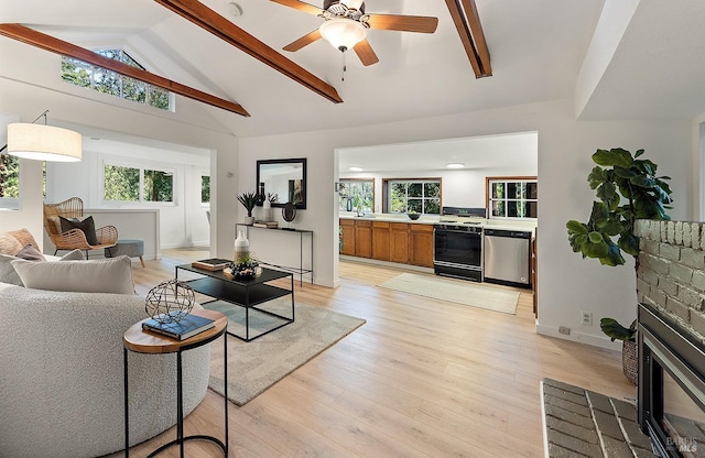living area with a brick fireplace, a ceiling fan, a healthy amount of sunlight, light wood finished floors, and lofted ceiling