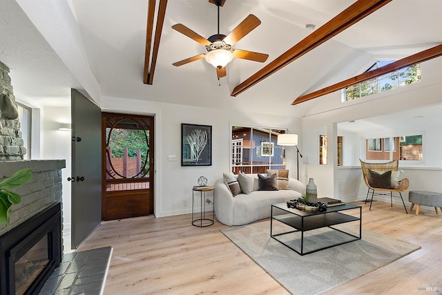 living area featuring baseboards, a fireplace, light wood-style flooring, ceiling fan, and high vaulted ceiling