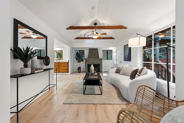 living room with ceiling fan, light wood-type flooring, vaulted ceiling, and a fireplace