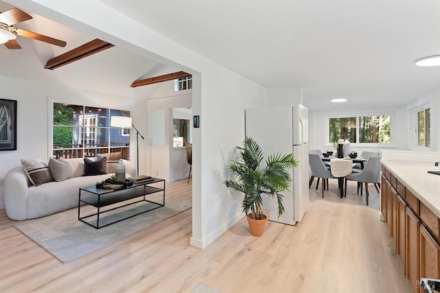 living area with a ceiling fan, light wood-type flooring, vaulted ceiling with beams, and visible vents
