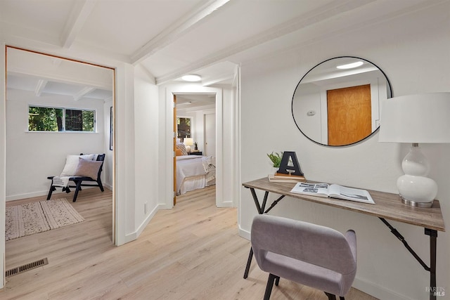 office space with light wood-style floors, baseboards, visible vents, and beam ceiling
