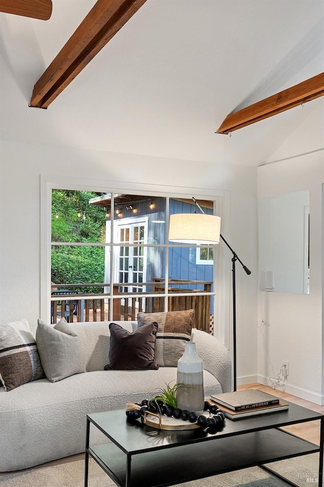 living area featuring baseboards, wood finished floors, and lofted ceiling with beams