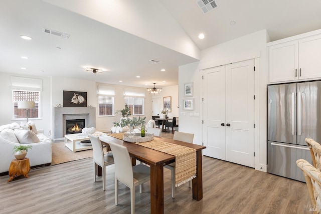 dining space featuring visible vents, recessed lighting, light wood-style floors, and a glass covered fireplace