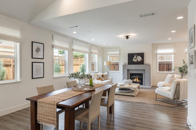 dining room featuring dark wood-style floors, a glass covered fireplace, visible vents, and recessed lighting