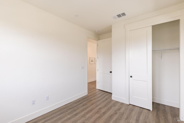 unfurnished bedroom featuring visible vents, baseboards, and wood finished floors